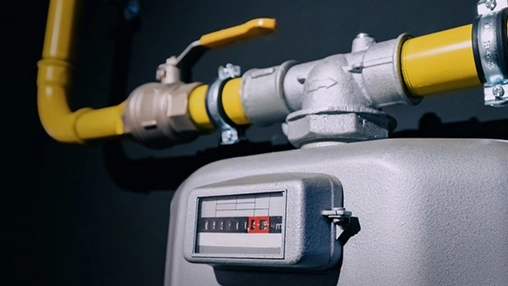 Industrial gas meter with mechanical counter and yellow pipeline valve and pipe fittings on a dark background
